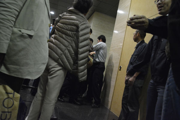 裁判所職員から力づくで法廷の外に出されていく傍聴者。=26日、東京高裁　写真：筆者=