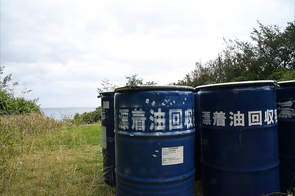 海岸入り口に並んだ漂着油回収用のドラム缶。環境汚染が紛れもなく起きたことを証明する。＝10日、奄美大島・土盛海岸　撮影：田中龍作＝