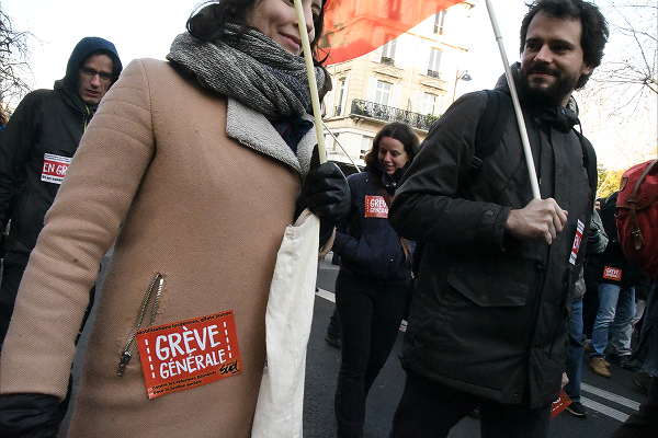 「ゼネストへ」。ワッペンをコートに貼って行進する労働者。＝14日、パリ市内　撮影：田中龍作＝