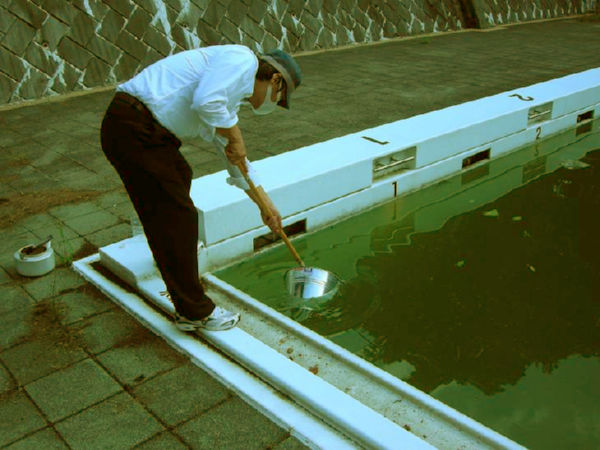 プールのたまり水を採取する川根眞也さん。（埼玉県内の中学校で。写真：川根氏提供）