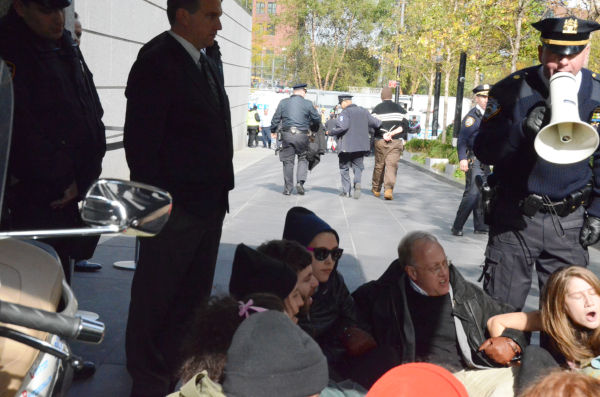 逮捕を覚悟で抗議の座り込みをするクリス・ヘッジズ記者（拡声器を持った警察官の左隣）。＝３日（現地時間）、ゴールドマン・サックスが入居するビルの玄関前。写真：筆者撮影＝