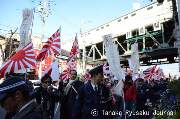 警察にガードされる格好で大阪随一のコリアタウンを民族排撃デモするレイシストたち。=2月24日、鶴橋　写真：田中撮影=