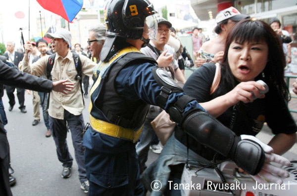 歩道上の抗議グループに向かって突っ込もうとし、機動隊に制止される女性リーダー。=写真：山田旬=
