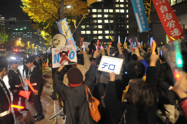 ペンライトをかざして抗議のシュプレヒコールをあげる参加者たち。＝写真：島崎ろでぃ＝