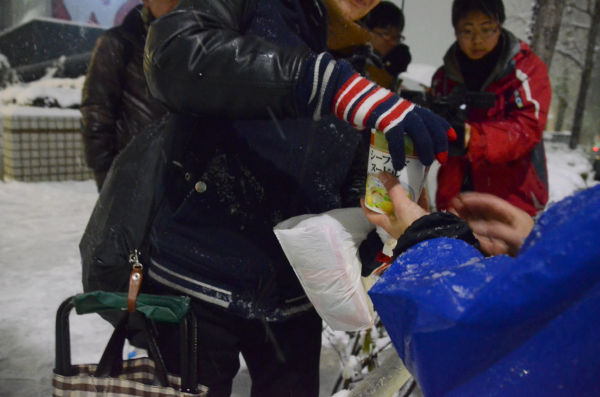 お湯を注いだカップヌードルを野宿者に手渡すボランティア（右）。＝14日夕、渋谷　写真：筆者＝