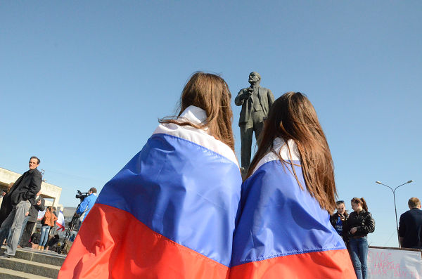 クリミアの州都シンフェロポルの広場にはロシア国旗を巻き付けた人の姿が目立った。奥はレーニン像。＝15日午後2時頃（日本時間午後9時頃）、クリミア政府庁舎前　写真：筆者＝