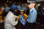 警察からゴボウ抜きにされる女性。参加者から怒号があがった。＝25日午後7時45分、公明党本部そば　写真：筆者＝