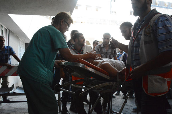 イスラエル軍の爆撃を受けアル・シファ病院に運び込まれた負傷者。手前がギルバート医師。=16日、ガザ市内　写真：筆者=