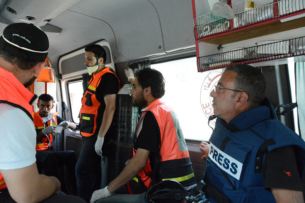 アル・シジャーイヤに向かう救急車の中。手前の防弾チョッキを着けている男性は、地元パレスチナ人記者。＝23日、アル・シジャーイヤ入口　写真：筆者＝