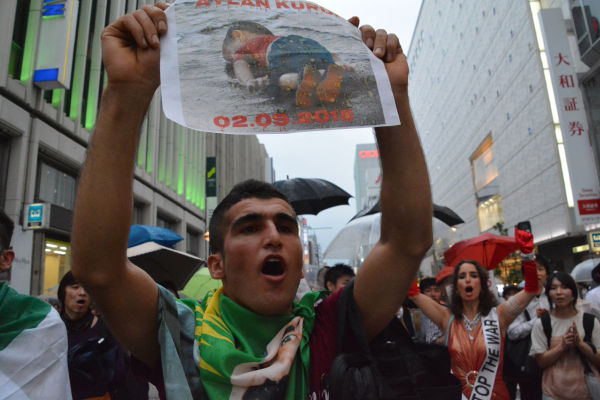 男児の写真を掲げて反戦を訴えるクルド青年。一枚の写真が世界を揺さぶっている。＝6日、新宿　田中撮影＝