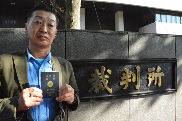 渡航制限のついたパスポートを持つ杉本さん。渡航制限のない本来のパスポートは外務省が保管している。=14日、東京地裁　写真：筆者=