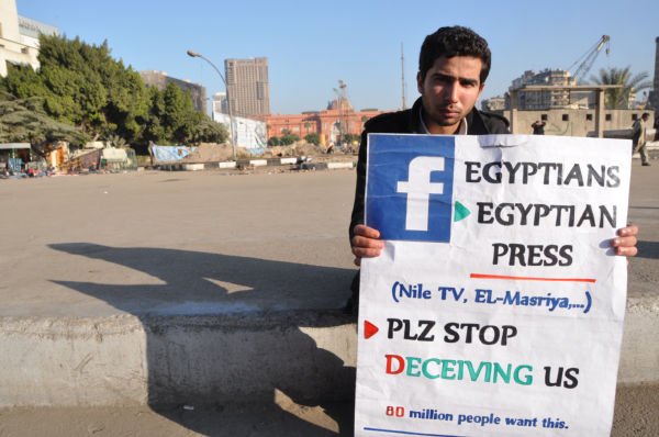 「エジプトの報道機関は国民をだましている」。青年は英語のプラカードを持ち海外メディアにアピールしていた。＝2011年2月、カイロ　撮影：筆者＝