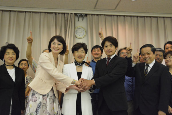 3人の候補予定者（左から吉田、円、原田氏）の周りで市民たちが1本指を立てた。=29日、杉並区内　撮影：筆者=