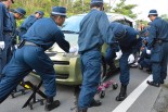 機動隊はヘリパッド建設に反対する住民・市民の車をジャッキ付きの荷車に乗せて次々と強制移動していった。=13日朝8時頃。東村高江　撮影：筆者=