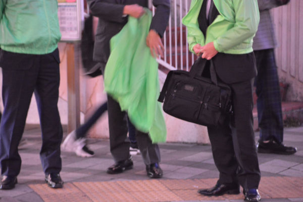 オッサン着替え中。演説会場に着きグリーンのジャンパーに着替える男たち。=15日夕方、万代シティ　撮影：筆者=