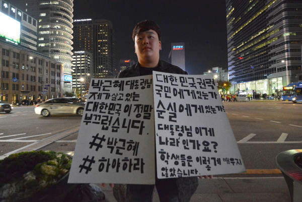 国民の政治リテラシーは高い。高校生の一人スタンディング。「韓国の権力は国民にあるのか、（崔）スンシルにあるのか。大統領にはこれが国なんですか」。=11日、ソウル・光化門交差点　撮影：筆者=