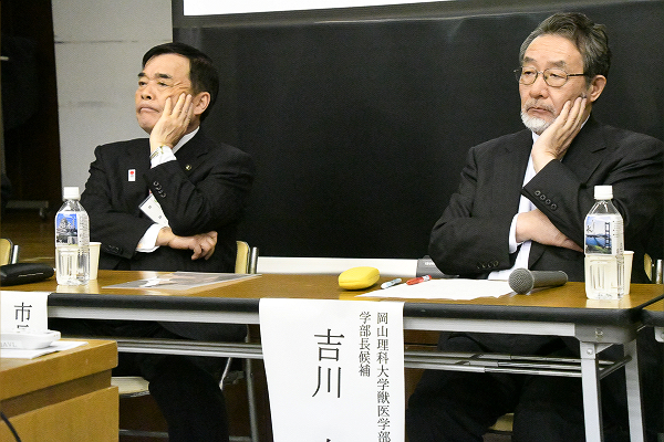 「やれやれ困ったな」。厳しい質問をぶつけられ頬に手をやる菅良二市長（左）と吉川康弘教授。= 11日夜、今治市民会館。撮影：筆者 =