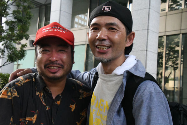 大袈裟太郎氏（左）と写真家の島崎ろでぃ氏。島崎氏も沖縄で逮捕された経験がある。米軍ヘリパッド建設のため高江の原生林が大規模伐採されていく様子をカメラで克明に記録していたのだった。＝7月、都内　撮影：筆者＝