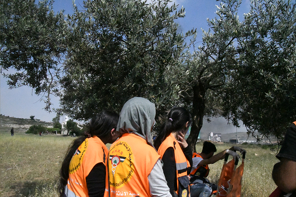 この日も女性救急隊員たちはオリーブの木陰から心配そうに戦況を見つめていた。＝15日、パレスチナ自治区アルビーレ村　撮影：田中龍作＝