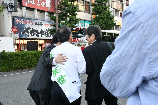 運動員（左端）は、肩を抱いて候補者を連れ去り、記者に質問させないようにした。＝2日、新潟市内　撮影：村上理央＝