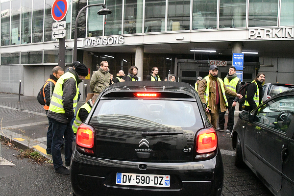黄色いベストたちは駐車場に入ろうとする職員の車を一台一台停めて、抗議を受付ける部署の連絡先を聞き出したが・・・＝22日、国営放送裏　撮影：田中龍作＝