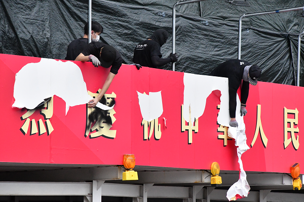 黒装束の若者たちは、デモ参加者に楽しんでもらうかのように『熱烈慶祝 中華人民共和国 建国70周年』の看板を剥がしていった。＝31日、金鐘　撮影：田中龍作＝