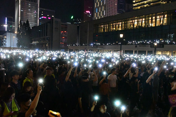 集会参加者はスマホのライトをかざしながら香港国歌の「Glory to HongKong」を合唱した。＝27日夜、エディンバラ広場　撮影：田中龍作＝