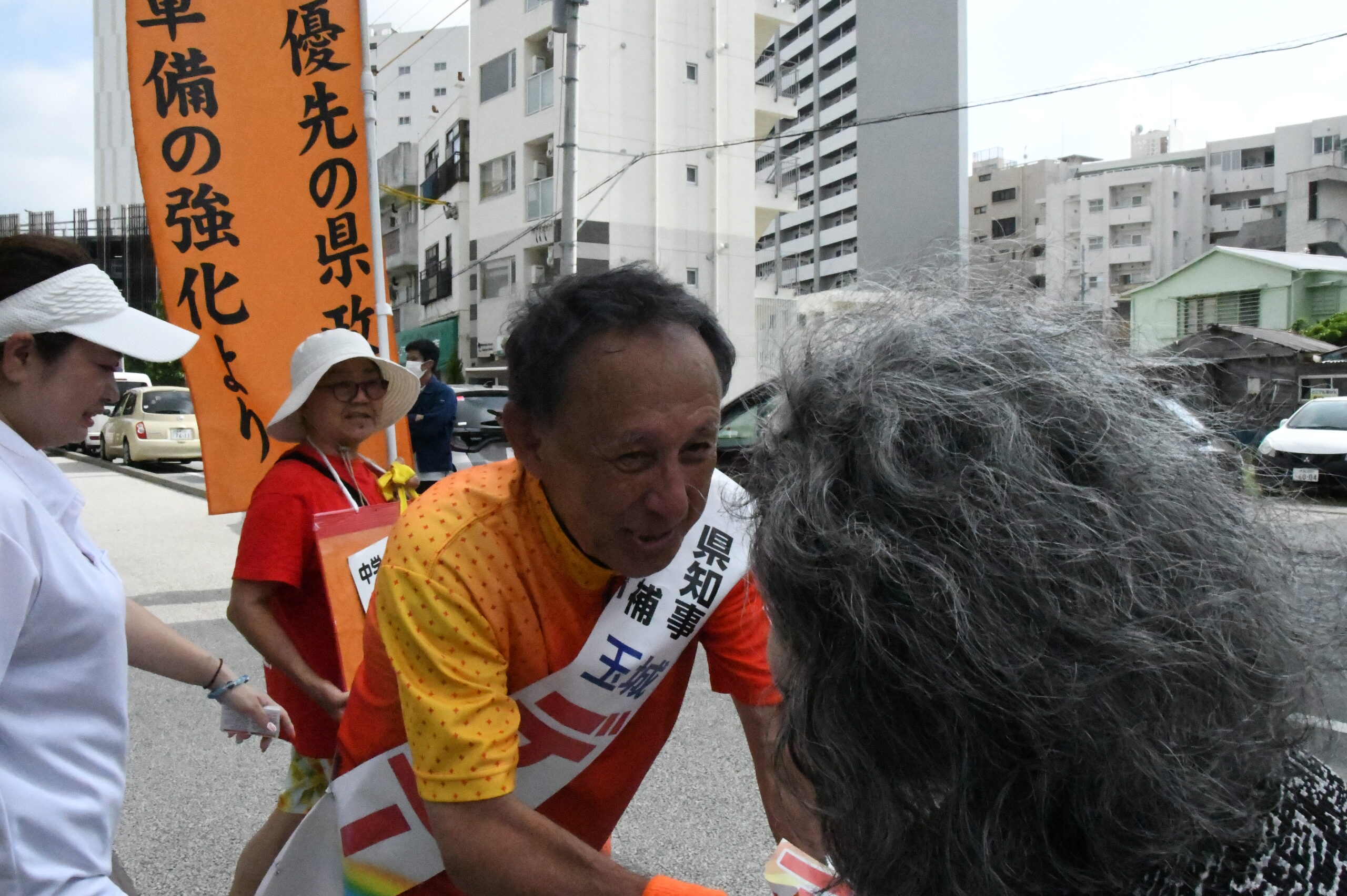 オバアの声に耳を傾けるデニー候補。=7日、那覇市内 撮影:田中龍作=